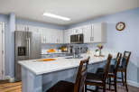 This modern kitchen features sleek white cabinetry and a spacious quartz island, perfect for meal prep and casual dining.
