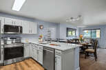 This modern kitchen features sleek white cabinetry, a spacious island with a built-in sink and dishwasher, and stainless steel appliances including a microwave and oven.