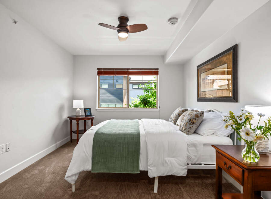This inviting bedroom features a comfortable queen-size bed adorned with crisp white linens and a stylish green throw.