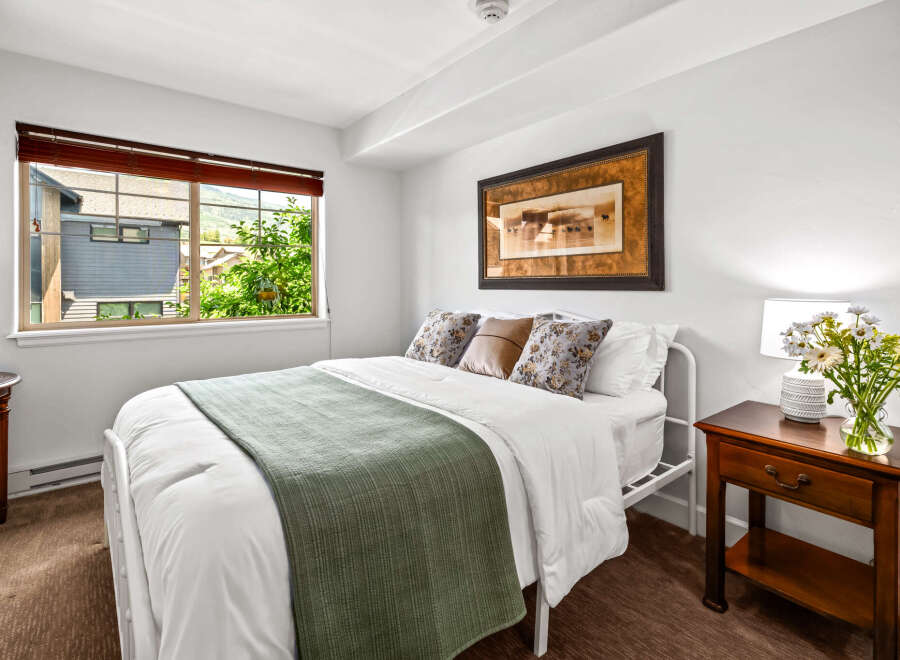 Experience comfort and style in this inviting bedroom, featuring a plush queen-size bed adorned with crisp white linens and a decorative green throw.