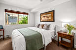 Experience comfort and style in this inviting bedroom, featuring a plush queen-size bed adorned with crisp white linens and a decorative green throw.