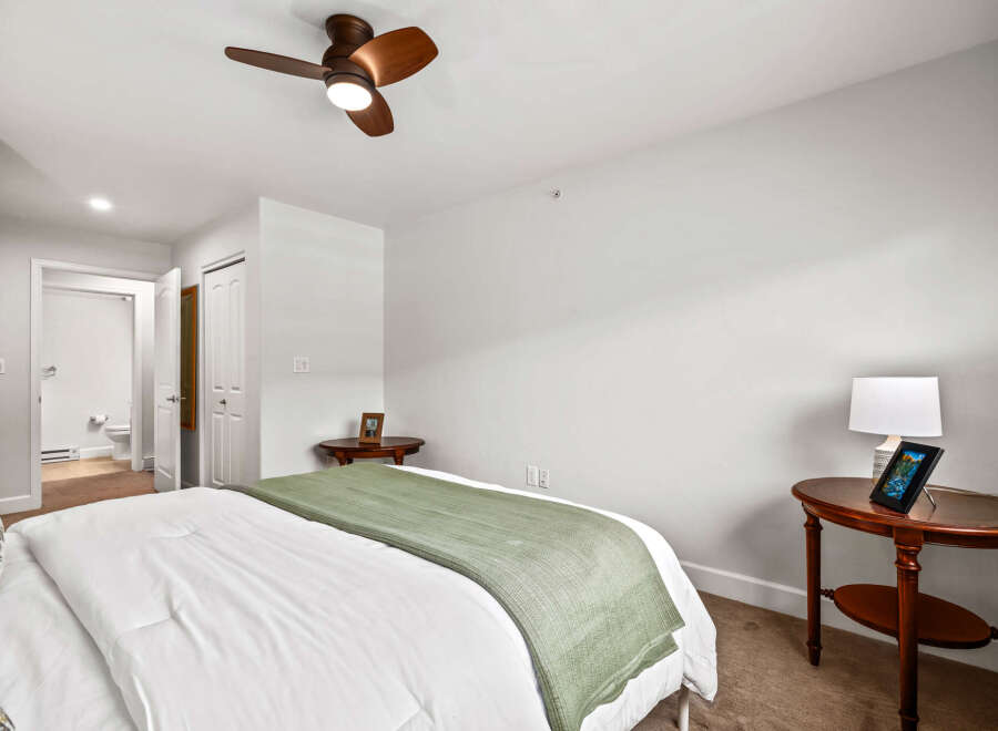 Experience comfort and style in this inviting bedroom, featuring a plush bed adorned with crisp white linens and a soothing green throw.