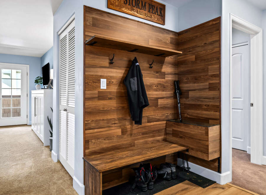 This entryway features a stylish wooden accent wall with a built-in bench and shelving, perfect for storing shoes and coats.