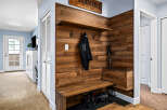 This entryway features a stylish wooden accent wall with a built-in bench and shelving, perfect for storing shoes and coats.