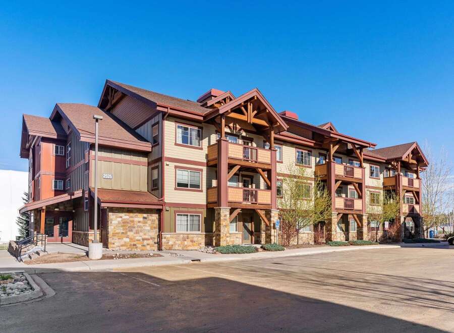 Experience mountain living in this stunning condo complex featuring a rustic architectural style with stone accents and exposed wooden beams.