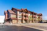 Experience mountain living in this stunning condo complex featuring a rustic architectural style with stone accents and exposed wooden beams.