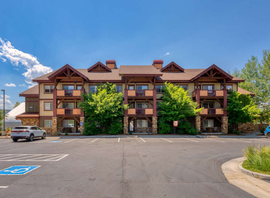 Discover comfortable living in this multi-story apartment building, featuring private balconies and a charming rustic exterior.