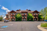 Discover comfortable living in this multi-story apartment building, featuring private balconies and a charming rustic exterior.