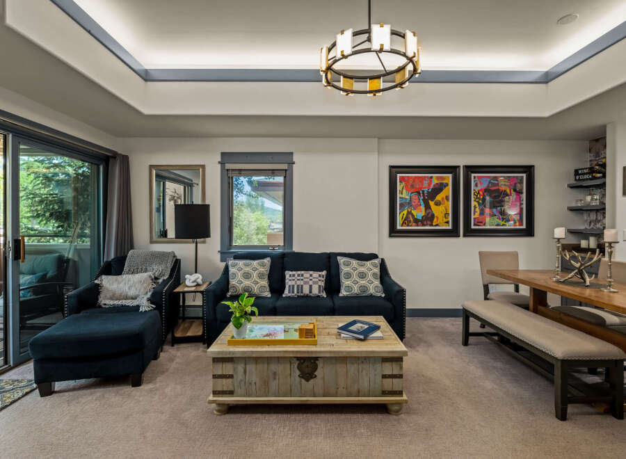 Experience modern living in this spacious living and dining area, featuring a comfortable navy blue sofa and a rustic wooden coffee table.
