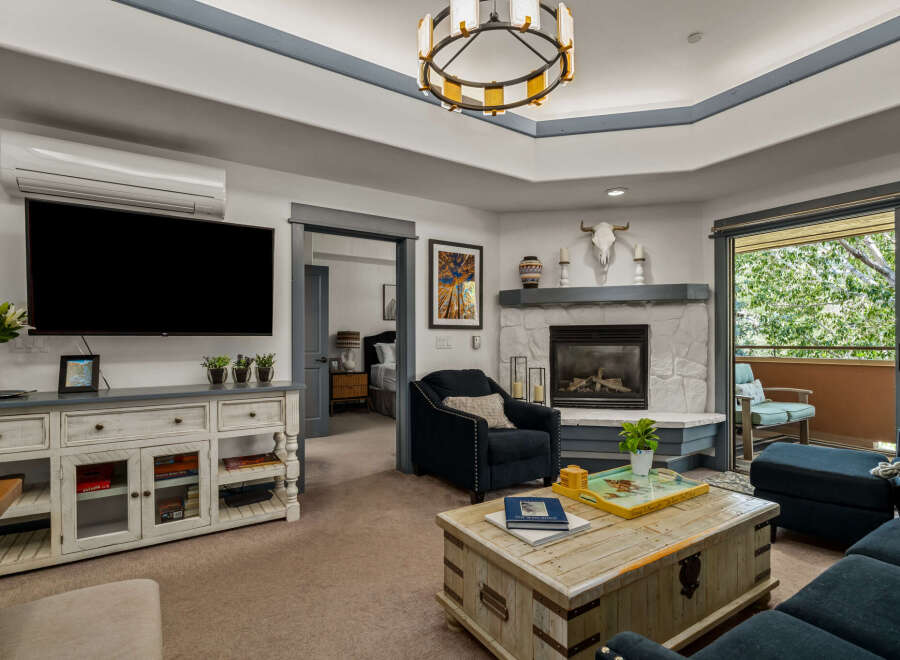 Experience comfort and style in this inviting living room, featuring a large flat-screen TV, a cozy fireplace, and ample seating.