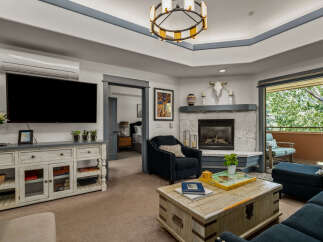 Experience comfort and style in this inviting living room, featuring a large flat-screen TV, a cozy fireplace, and ample seating.