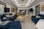 Experience modern living in this spacious open-concept home, featuring a stylish living area with plush navy seating and a unique distressed wood coffee table.