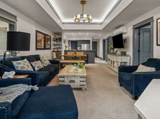 Experience modern living in this spacious open-concept home, featuring a stylish living area with plush navy seating and a unique distressed wood coffee table.