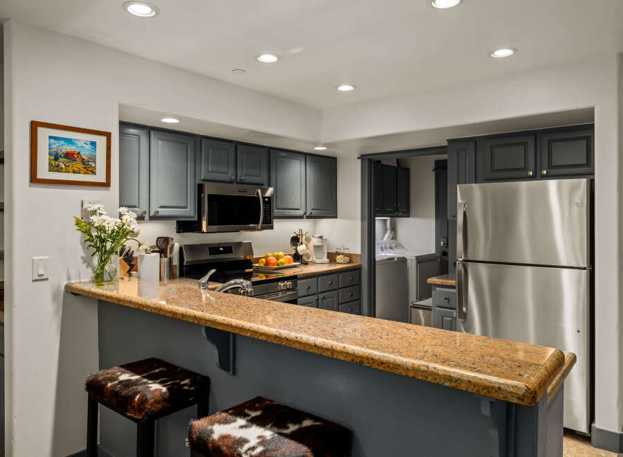 This charming kitchen features sleek, dark gray cabinetry complemented by a stunning granite countertop breakfast bar.
