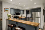 This charming kitchen features sleek, dark gray cabinetry complemented by a stunning granite countertop breakfast bar.