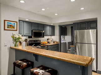 This charming kitchen features sleek, dark gray cabinetry complemented by a stunning granite countertop breakfast bar.