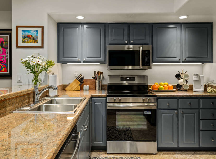 This modern kitchen features sleek, dark gray cabinetry complemented by a stunning granite countertop.