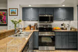 This modern kitchen features sleek, dark gray cabinetry complemented by a stunning granite countertop.