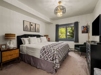 Experience ultimate comfort in this beautifully appointed bedroom, featuring a plush king-size bed adorned with crisp white linens and a striking geometric-patterned throw.
