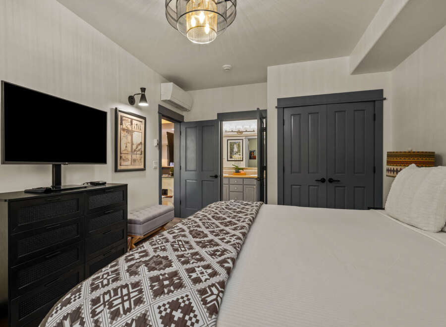 Experience ultimate comfort in this beautifully appointed bedroom, featuring a large flat-screen TV for entertainment and ample storage with a stylish dresser.