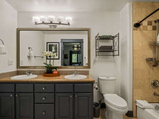 This spacious bathroom features a double vanity with ample counter space and dark gray cabinetry, perfect for storage.