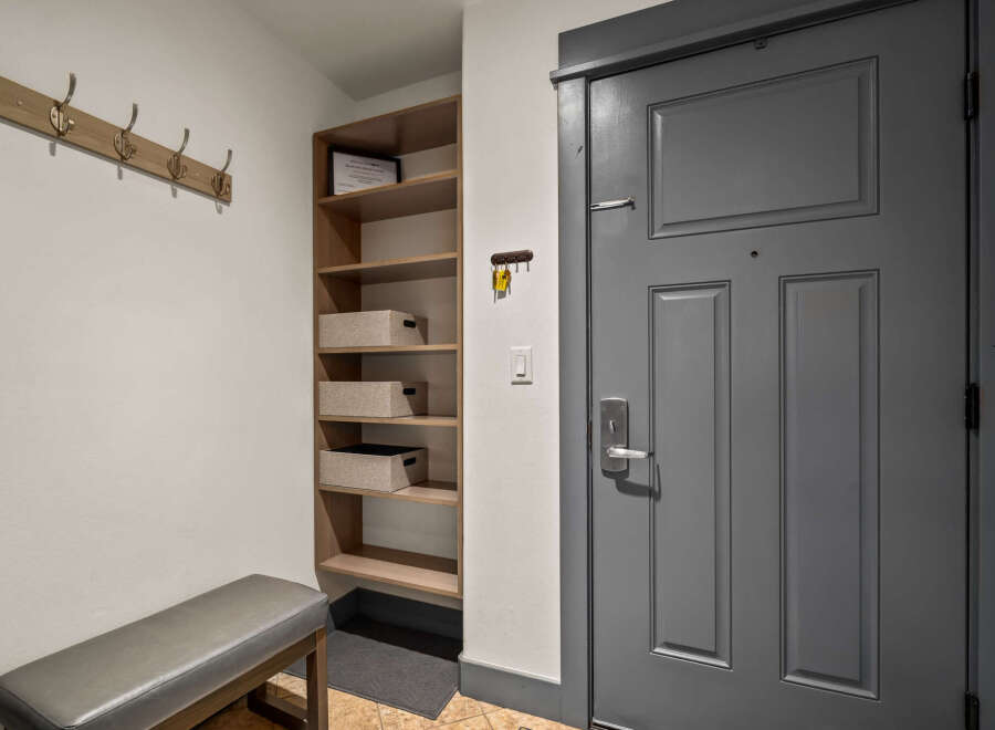 Welcome to this charming entryway, featuring a convenient coat rack and a stylish bench for putting on shoes.