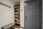Welcome to this charming entryway, featuring a convenient coat rack and a stylish bench for putting on shoes.