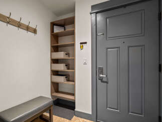 Welcome to this charming entryway, featuring a convenient coat rack and a stylish bench for putting on shoes.