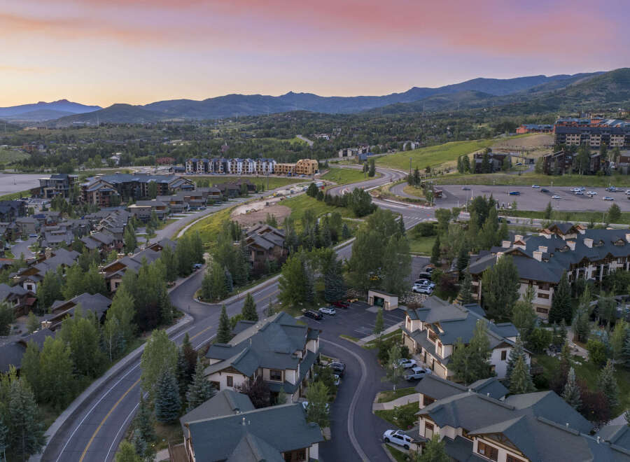 Experience luxury mountain living in this stunning aerial view of a residential community nestled amidst rolling hills and majestic peaks.