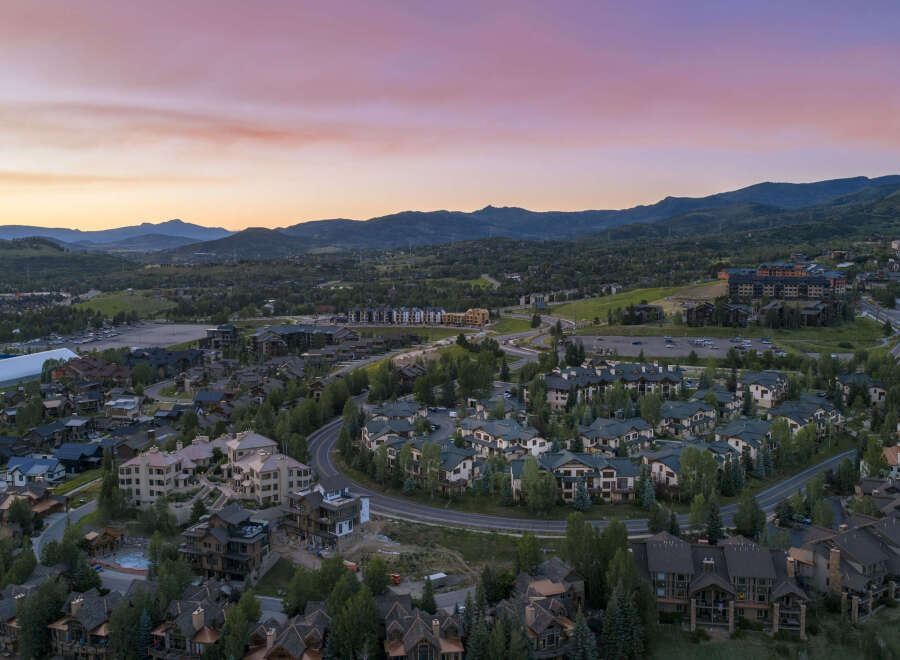 Experience luxury mountain living in this stunning aerial view of a residential community nestled amidst rolling hills and majestic peaks.