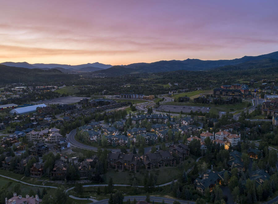 Experience luxury mountain living in this stunning aerial view of a residential community nestled amidst rolling hills and majestic mountains.