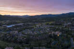 Experience luxury mountain living in this stunning aerial view of a residential community nestled amidst rolling hills and majestic mountains.