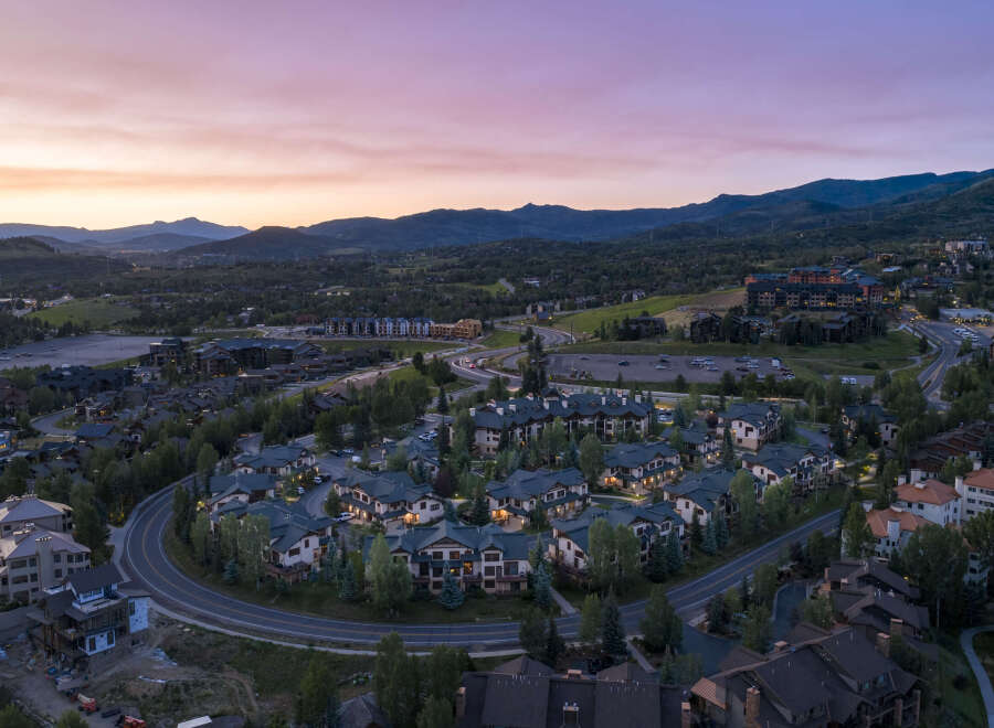 Experience luxury mountain living in this stunning aerial view of a residential community nestled amidst rolling hills and majestic mountains.