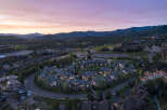 Experience luxury mountain living in this stunning aerial view of a residential community nestled amidst rolling hills and majestic mountains.