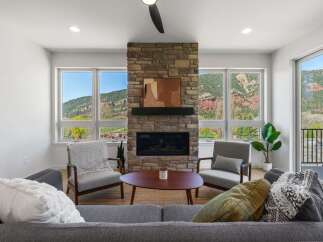 Experience breathtaking mountain views from this stunning living room, featuring a grand stone fireplace as the centerpiece.