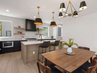 Experience modern living in this stunning kitchen featuring sleek black cabinetry, a spacious island with bar seating, and a striking black range hood.