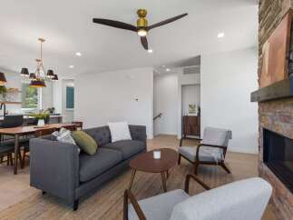 Experience modern living in this open-concept space, featuring a stylish gray tufted sofa and comfortable armchairs perfect for relaxation.