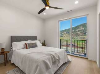 Experience breathtaking mountain views from this stunning bedroom, featuring a luxurious king-size bed and a modern ceiling fan.