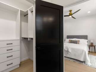 Step into a beautifully designed bedroom featuring a modern black barn door that opens to reveal a spacious closet with ample storage.