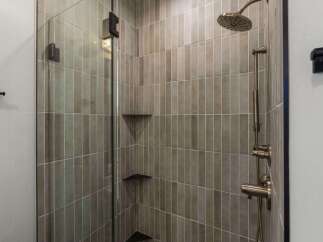 Experience modern luxury in this stunning walk-in shower, featuring sleek vertical tilework and a convenient glass enclosure.