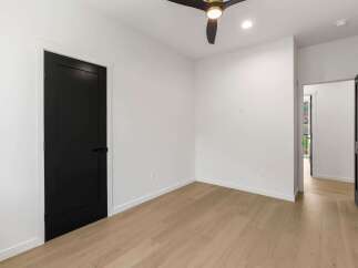 Step into this modern bedroom featuring a sleek black shaker door and a stylish ceiling fan with a gold accent.