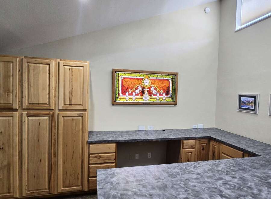 Discover this spacious room featuring ample storage with tall wooden cabinets and a custom L-shaped countertop, perfect for a home office or craft area.