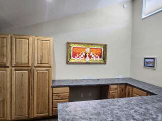 Discover this spacious room featuring ample storage with tall wooden cabinets and a custom L-shaped countertop, perfect for a home office or craft area.