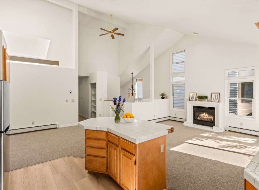 Experience spacious living in this open-concept home featuring a vaulted ceiling with a ceiling fan and a cozy fireplace.