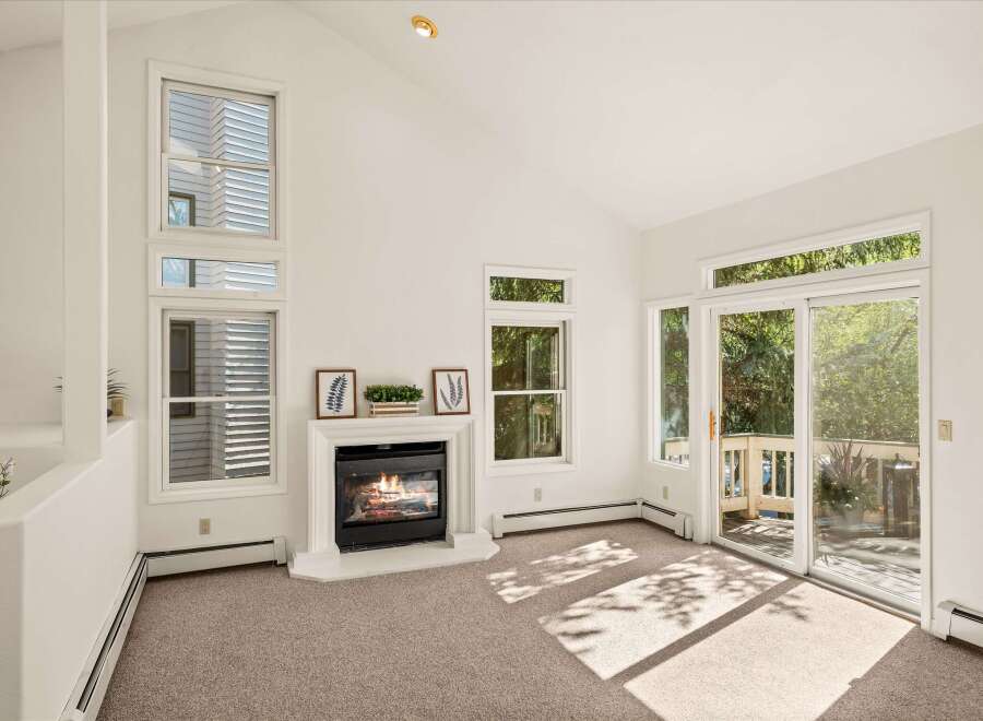 Experience cozy evenings by the fireplace in this inviting living room, featuring a vaulted ceiling and abundant natural light.