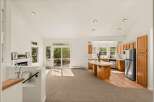 This spacious open-concept living area features a cozy fireplace, a large sliding glass door leading to an outdoor deck, and a well-appointed kitchen with a central island.