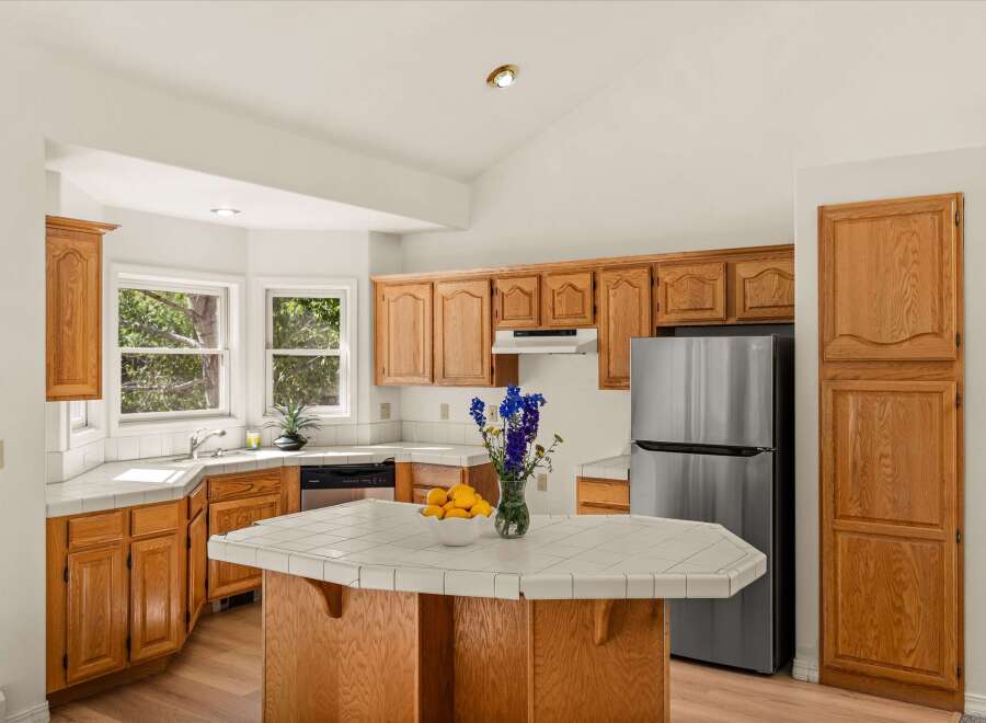 This spacious kitchen features warm oak cabinetry and a tiled island, perfect for meal preparation and casual dining.
