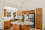 This spacious kitchen features warm oak cabinetry and a tiled island, perfect for meal preparation and casual dining.