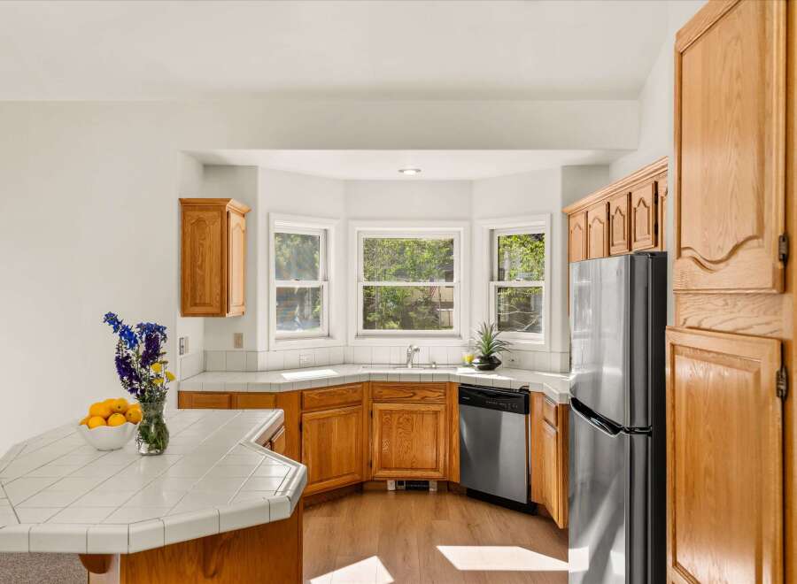 This charming kitchen features warm oak cabinetry and a spacious bay window that floods the space with natural light.