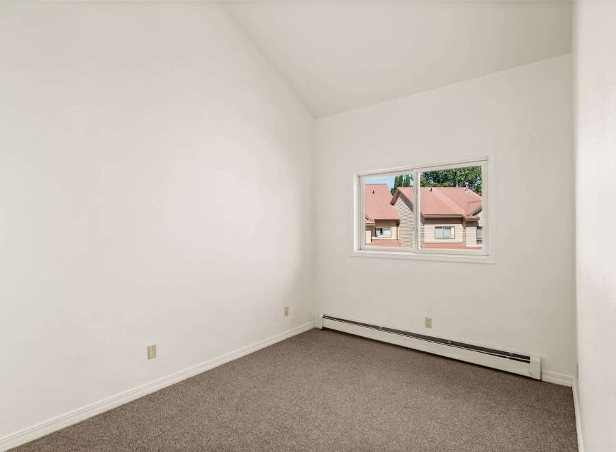 Discover this charming room featuring a vaulted ceiling and a large window that floods the space with natural light.